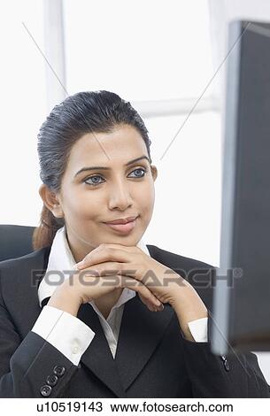 Stock Image - Close-up of a businesswoman sitting in front of a computer with her hands clasped. Fotosearch