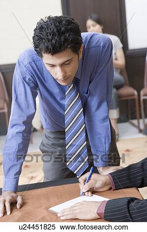 Person's hands writing on a paper and a businessman looking at it View Large Photo Image Stock Photography - Person's hands writing on a paper and a businessman looking at it. Fotosearch
