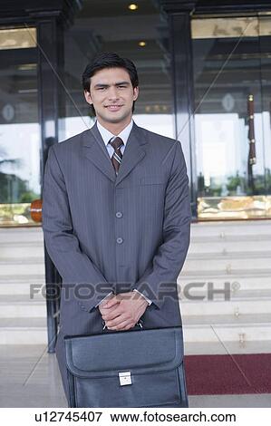 Stock Photo - Portrait of a businessman holding a bag and smiling. Fotosearch