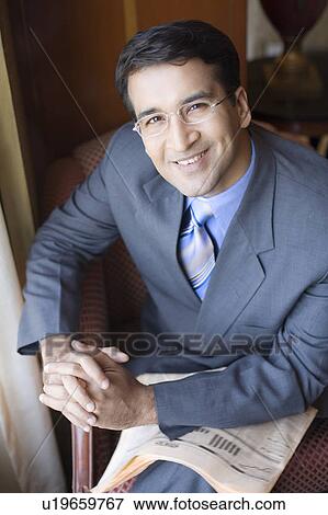 Stock Photo - Portrait of a businessman smiling with a newspaper on his lap. Fotosearch