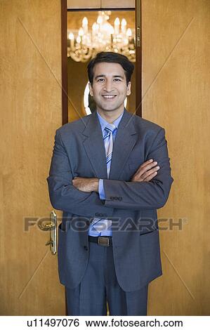 Stock Photograph - Portrait of a businessman standing with his arms crossed and smiling. Fotosearch