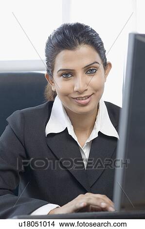 Portrait of a businesswoman sitting in front of a computer and smiling View Large Photo Image Picture - Portrait of a businesswoman sitting in front of a computer and smiling. Fotosearch