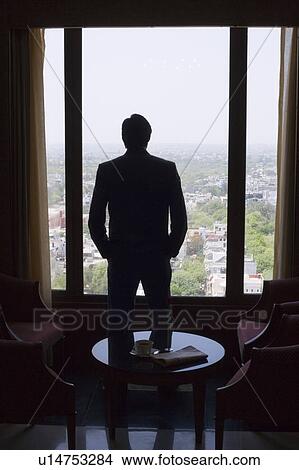 Picture - Rear view of a businessman looking through a window. Fotosearch