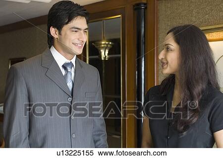 Businessman and a businesswoman talking to each other and smiling in a hotel View Large Photo Image Stock Photography - Businessman and a businesswoman talking to each other and smiling in a hotel. Fotosearch