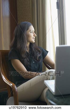 Stock Image - Businesswoman sitting on a chair in front of a laptop in a hotel. Fotosearch