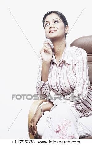 Businesswoman sitting on a chair talking on a mobile phone View Large Photo Image Stock Photo - Businesswoman sitting on a chair talking on a mobile phone. Fotosearch