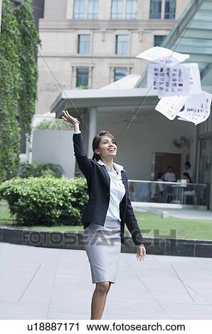 Stock Image - Businesswoman throwing papers in air, Singapore. Fotosearch
