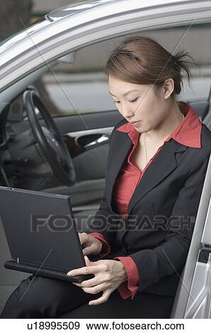 Businesswoman using a laptop in a car, Singapore View Large Photo Image Stock Photo - Businesswoman using a laptop in a car, Singapore. Fotosearch