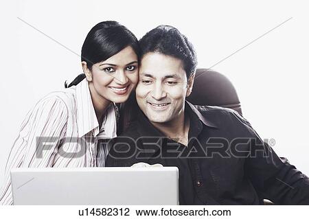 Close-up of a businessman and a businesswoman sitting in front of a laptop View Large Photo Image Stock Image - Close-up of a businessman and a businesswoman sitting in front of a laptop. Fotosearch