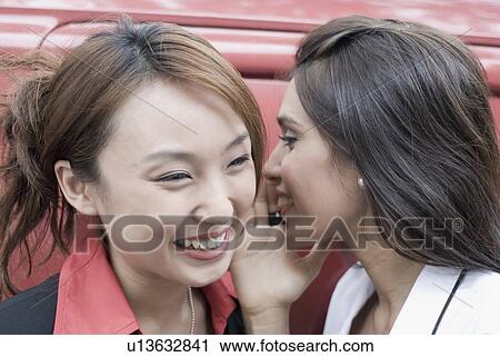 Close-up of a businesswoman whispering into an another businesswoman's ear and smiling View Large Photo Image Stock Image - Close-up of a businesswoman whispering into an another businesswoman's ear and smiling. Fotosearch