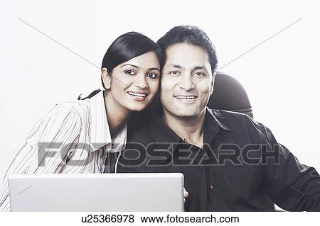 Stock Photo - Portrait of a businessman and a businesswoman sitting in front of a laptop. Fotosearch