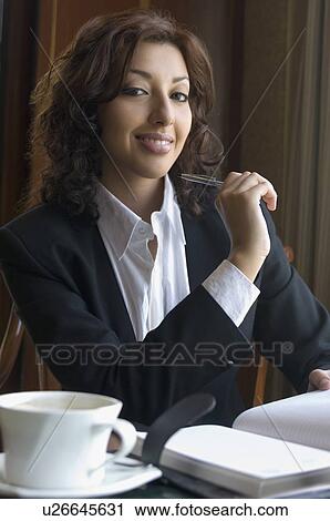Stock Image - Portrait of a businesswoman holding a pen and smiling. Fotosearch
