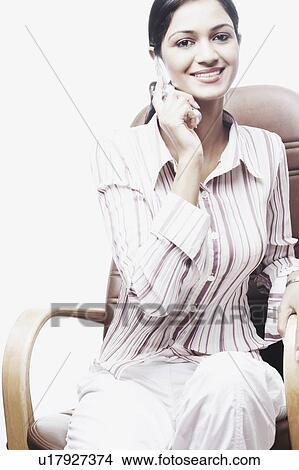 Picture - Portrait of a businesswoman sitting on a chair and talking on a mobile phone. Fotosearch