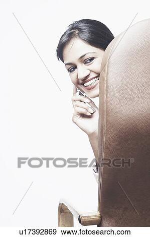 Portrait of a businesswoman sitting on a chair talking on a mobile phone View Large Photo Image Stock Photo - Portrait of a businesswoman sitting on a chair talking on a mobile phone. Fotosearch