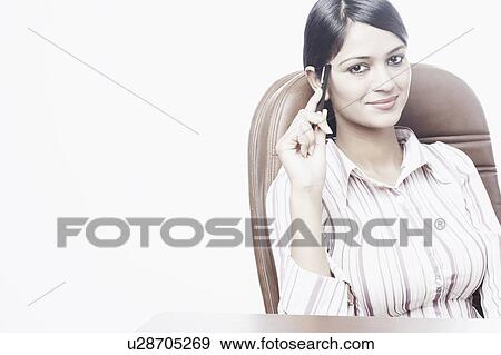 Portrait of a businesswoman sitting on a chair holding a pen View Large Photo Image Stock Photo - Portrait of a businesswoman sitting on a chair holding a pen. Fotosearch