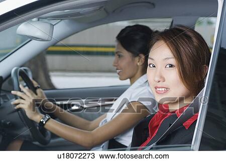 Portrait of a businesswoman smiling with another businesswoman driving a car View Large Photo Image Stock Image - Portrait of a businesswoman smiling with another businesswoman driving a car. Fotosearch