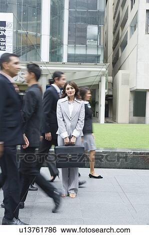 Portrait of a businesswoman standing with business executives walking on the road View Large Photo Image Stock Photograph - Portrait of a businesswoman standing with business executives walking on the road. Fotosearch