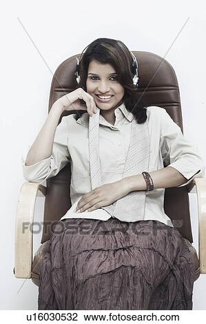 Stock Image - Portrait of a businesswoman wearing headphones sitting on an office chair. Fotosearch
