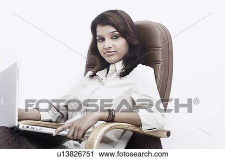 Portrait of a businesswoman with a laptop on her lap sitting on an office chair View Large Photo Image Stock Image - Portrait of a businesswoman with a laptop on her lap sitting on an office chair. Fotosearch