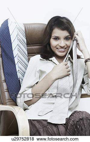 Portrait of a businesswoman with a tie in her hand sitting on an office chair View Large Photo Image Stock Photo - Portrait of a businesswoman with a tie in her hand sitting on an office chair. Fotosearch
