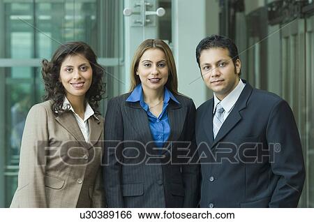 Stock Photograph - Portrait of two businesswomen smiling with a businessman. Fotosearch