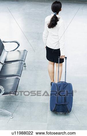 Rear view of a businesswoman holding a luggage at an airport View Large Photo Image Stock Image - Rear view of a businesswoman holding a luggage at an airport. Fotosearch