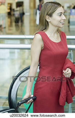 Side profile of a businesswoman pulling her luggage View Large Photo Image Picture - Side profile of a businesswoman pulling her luggage. Fotosearch