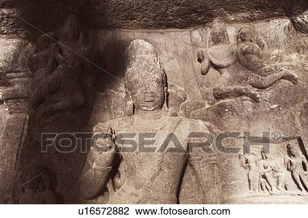 Stock Image - Statues carved on the wall in a cave, Ellora, Aurangabad, Maharashtra, India. Fotosearch