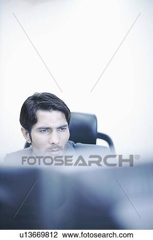 Stock Image - High angle view of a businessman sitting in an office. Fotosearch