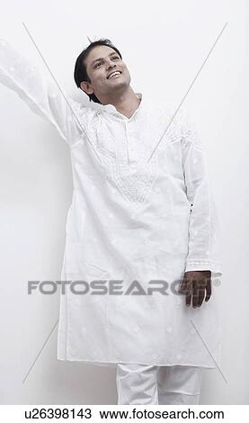 Stock Image - Mid adult man standing with his hand raised. Fotosearch