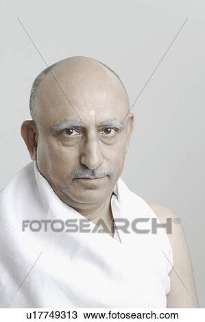Stock Image - Portrait of a mature man impersonating Mahatma Gandhi. Fotosearch