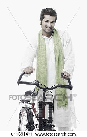 Stock Image - Portrait of a young man standing with a bicycle. Fotosearch
