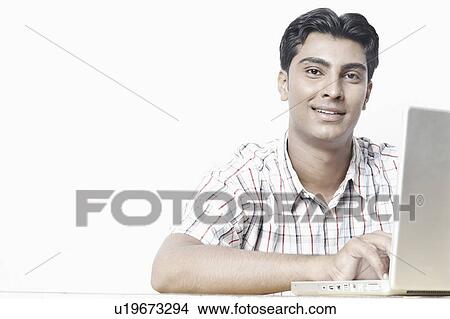 Portrait of a young man working on a laptop View Large Photo Image Picture - Portrait of a young man working on a laptop. Fotosearch