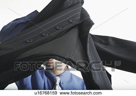 Stock Photo - Young man holding a coat in front of his face. Fotosearch