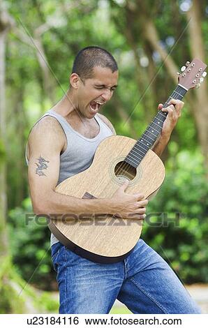 Stock Photograph - Young man playing a guitar and singing. Fotosearch