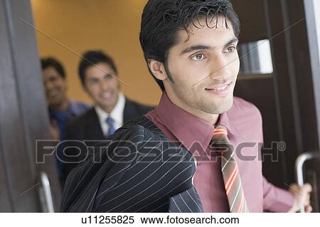 Close-up of a businessman moving out from a conference room with his colleagues standing in the background View Large Photo Image Stock Photography - Close-up of a businessman moving out from a conference room with his colleagues standing in the background. Fotosearch