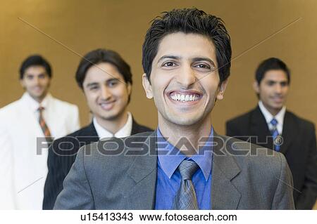 Close-up of a businessman smiling with three business executives standing behind him View Large Photo Image Stock Image - Close-up of a businessman smiling with three business executives standing behind him. Fotosearch
