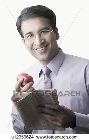Portrait of a businessman holding an apple and a newspaper View Large Photo Image Picture - Portrait of a businessman holding an apple and a newspaper. Fotosearch