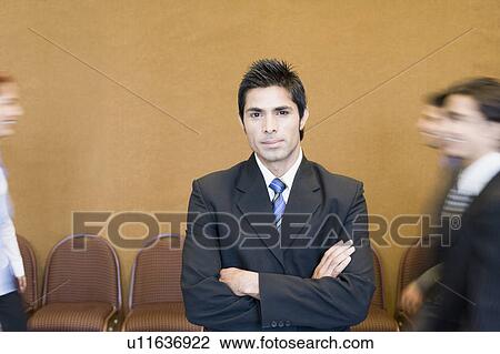 Stock Image - Portrait of a businessman standing with his arms crossed. Fotosearch