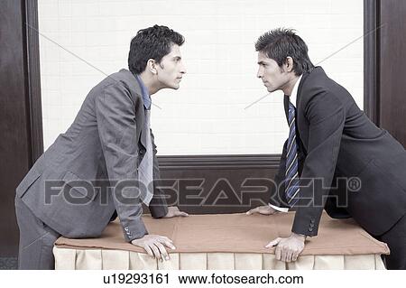 Side profile of two businessmen looking at each other View Large Photo Image Stock Image - Side profile of two businessmen looking at each other. Fotosearch