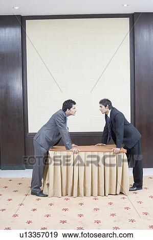 Stock Photo - Side profile of two businessmen looking at each other. Fotosearch