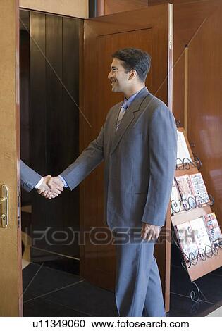 Side profile of two businessmen shaking hands at the door in a lobby View Large Photo Image Stock Image - Side profile of two businessmen shaking hands at the door in a lobby. Fotosearch