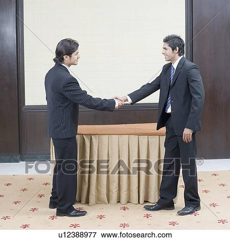 Side profile of two businessmen shaking their hands View Large Photo Image Stock Photo - Side profile of two businessmen shaking their hands. Fotosearch