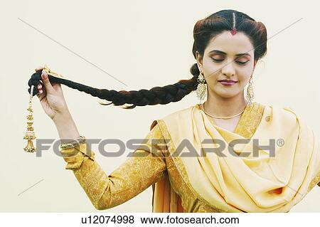 Close-up of a young woman holding her plait with her eyes closed View Large Photo Image Stock Photo - Close-up of a young woman holding her plait with her eyes closed. Fotosearch