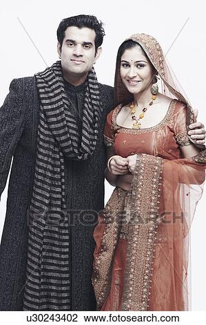 Portrait of a newlywed couple standing with their arms around each other View Large Photo Image Stock Image - Portrait of a newlywed couple standing with their arms around each other. Fotosearch
