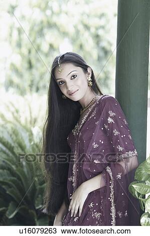Stock Image - Portrait of a teenage girl in a traditional dress leaning against a column. Fotosearch