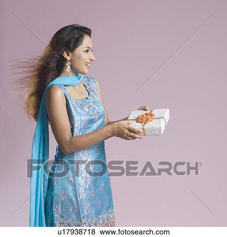 Stock Photo - Side profile of a mid adult woman in salwar kameez and holding a gift box. Fotosearch