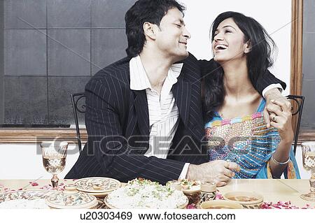 Young couple with arm around sitting at the dining table View Large Photo Image Stock Photo - Young couple with arm around sitting at the dining table. Fotosearch