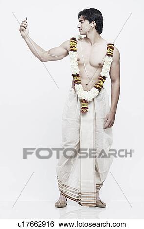 Stock Photograph - Young man in traditional clothing listening to an MP3 player. Fotosearch