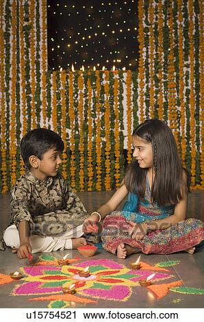 Stock Image - Boy and his sister making rangoli. Fotosearch